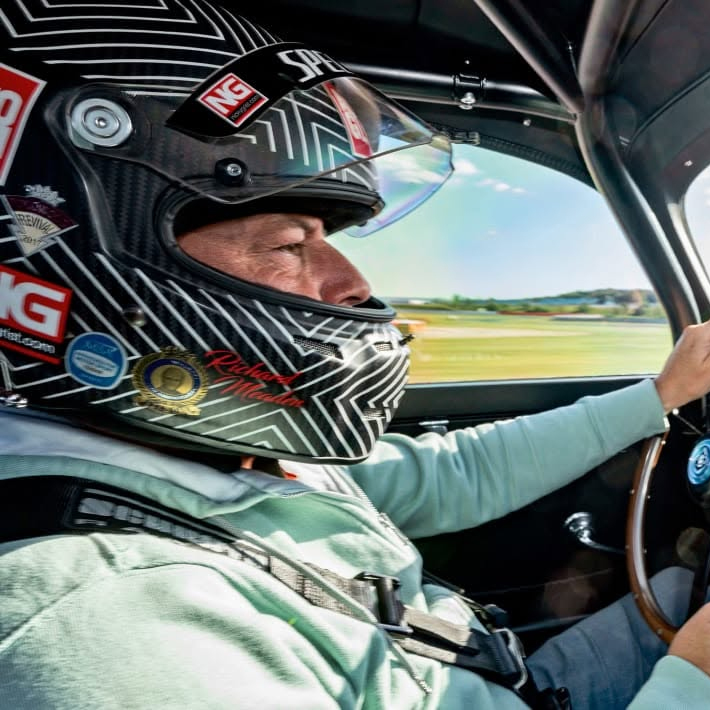 Richard « Dickie » Meaden, pilote et essayeur pour EVO Magazine, au volant en combinaison bleu clair et casque carbone à son nom.